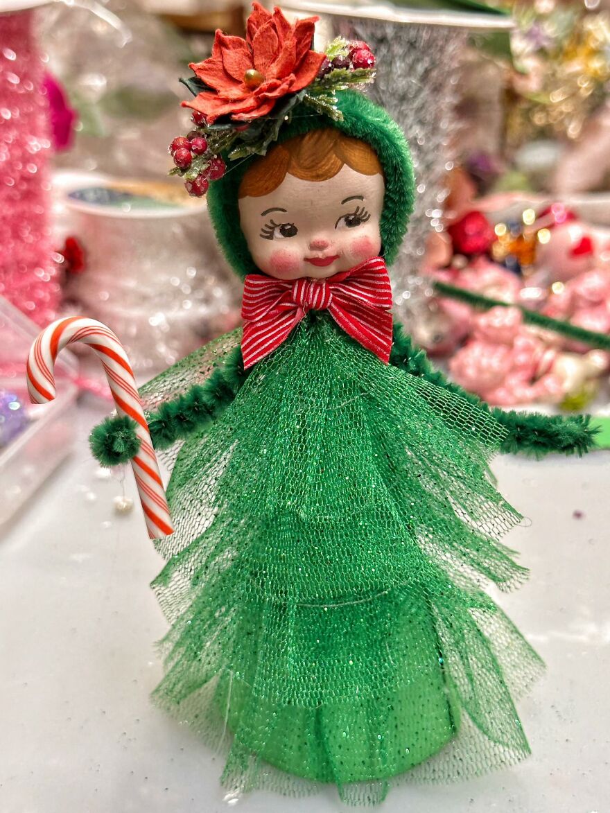 Vintage Christmas decoration doll dressed as a tree with a candy cane and red flower, evoking nostalgic holiday charm.