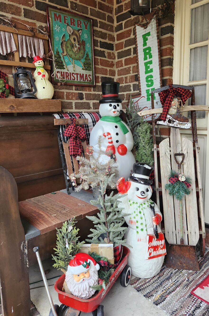 Vintage Christmas decorations including snowmen, Santa figure, sled, and nostalgic holiday signs in a cozy rustic setting.
