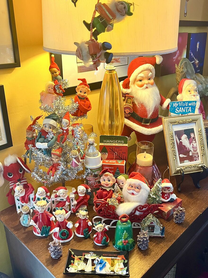 Vintage Christmas decorations display featuring Santa figurines, elves, and nostalgic holiday ornaments on a wooden table.