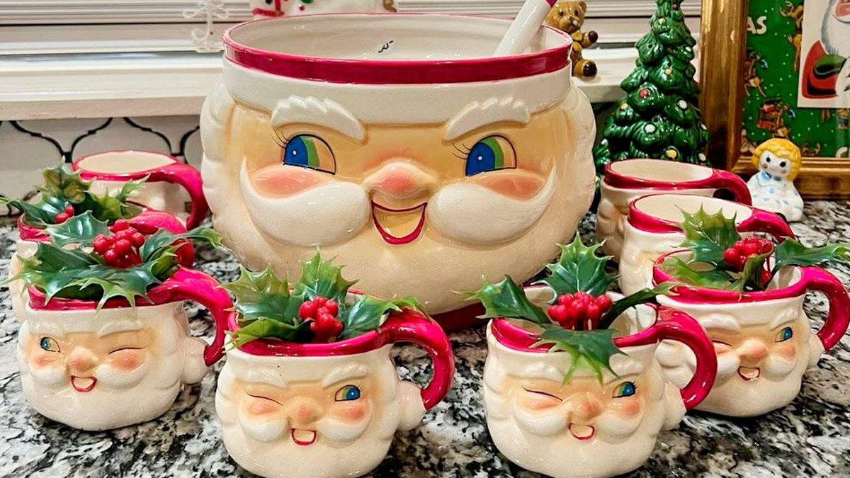 Vintage Christmas decorations featuring ceramic Santa mugs and a large Santa pitcher with festive holly accents on a countertop.
