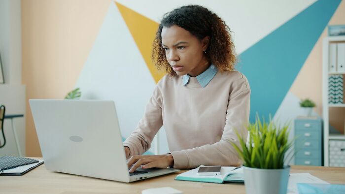 Woman working on laptop, looking frustrated, representing infuriating moments while working and feeling underpaid.