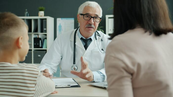 Doctor with stethoscope explaining health risks of everyday things to a woman and child during a consultation.