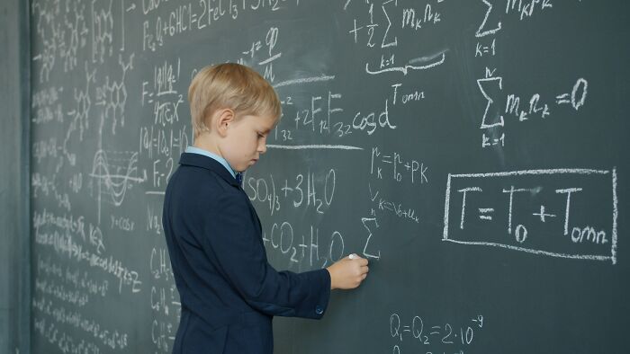 Young boy solving complex math problems on a chalkboard, illustrating challenges and lessons from revenge stories.
