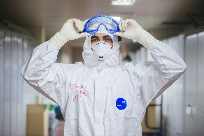 Scientist in full protective gear adjusting goggles, highlighting disturbing science facts with safety measures in a lab environment.