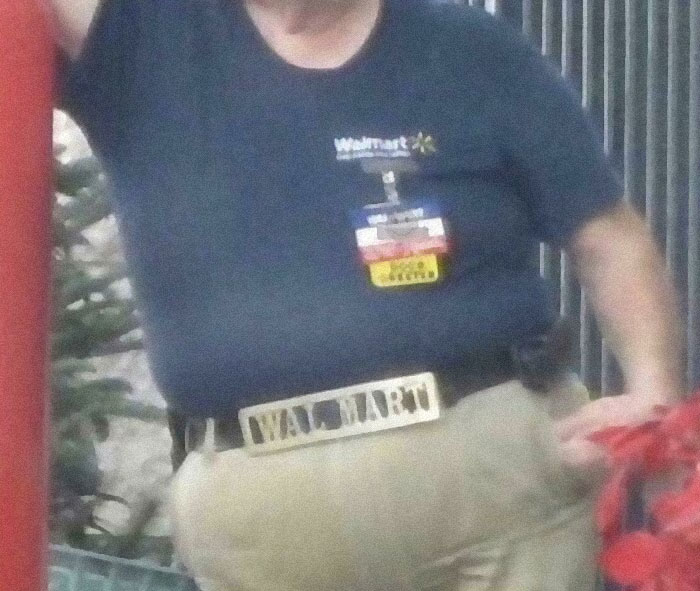 Person wearing a Walmart shirt and badge with a Walmart belt buckle in a casual indoor setting.