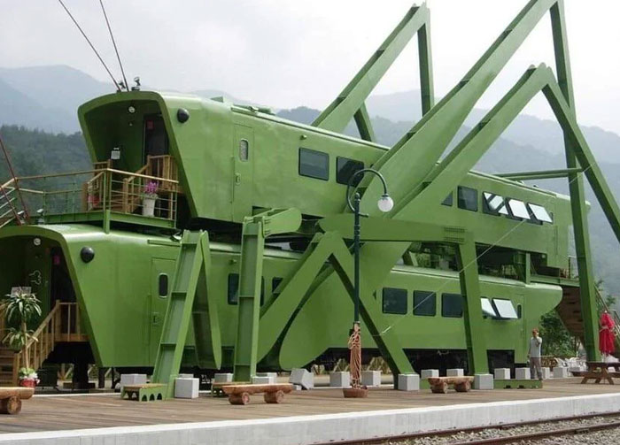 Unique green bread-shaped bread factory building with large windows and exterior structural supports in a mountainous area.