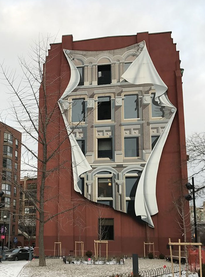 Building with a large mural that looks like a peeled-back layer revealing a detailed bread-shaped bread factory facade.