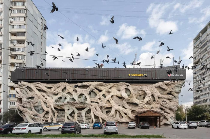 Building with intricate, bread-shaped facade resembling a bread-shaped bread factory in an urban setting with parked cars and birds.