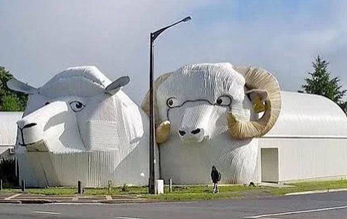 Large sheep-shaped building with curved horns and detailed facial features, an example of weird bread-shaped bread factory architecture.