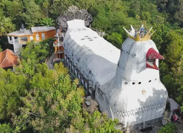 Bread-shaped bread factory building with a crown, nestled in lush greenery, showcasing unique architectural design.