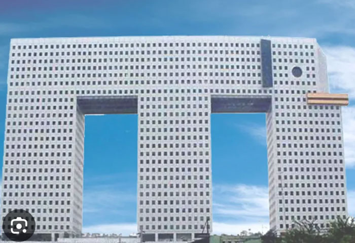 Bread-shaped bread factory building with rectangular windows under a bright blue sky, an example of weird architecture.