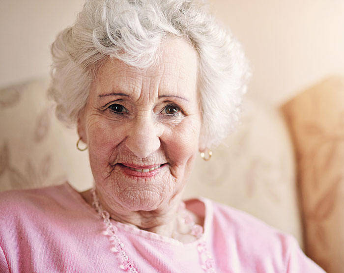 Elderly woman smiling gently, representing surprising family DNA test results revealing unusual sibling and parent relationships.