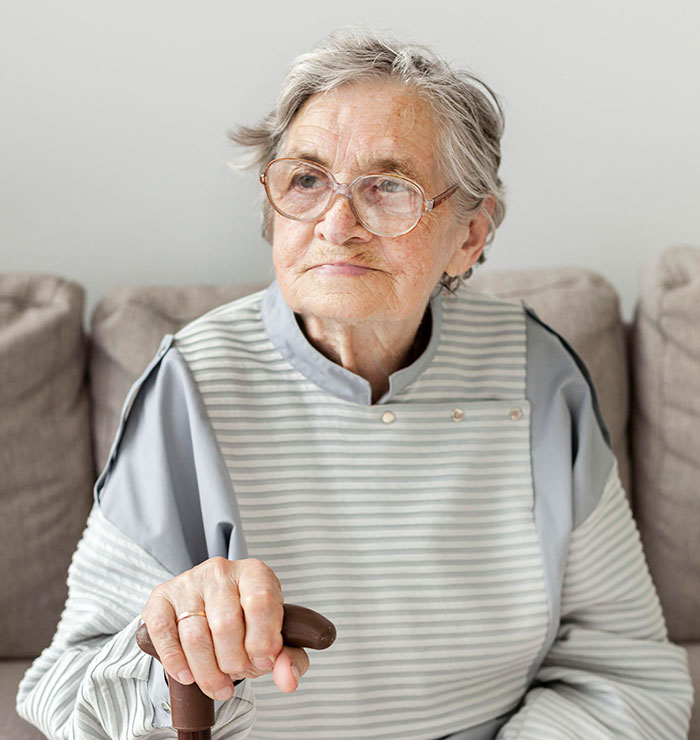 Elderly woman with glasses holding a cane, reflecting on shocking DNA tests revealing unexpected family roles.