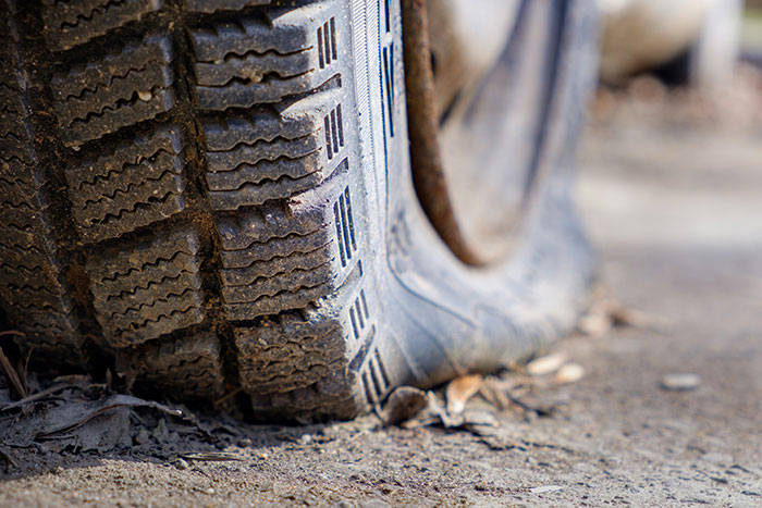 Close-up of a flat tire on a dirty road, illustrating one of the strange excuses for missing work.