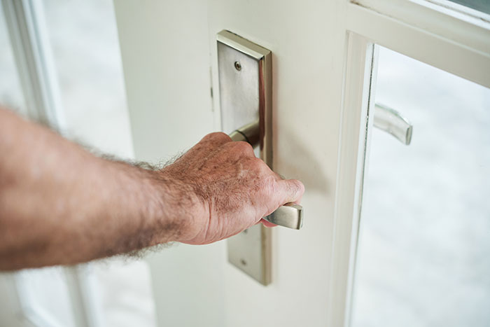 Hand gripping a door handle inside a house, illustrating a strange excuse for missing work involving a chinchilla ate her wallet.
