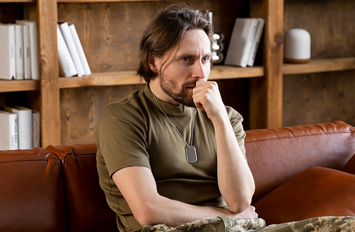 Man in casual clothes sitting on a leather couch looking thoughtful, illustrating strange excuses for missing work.