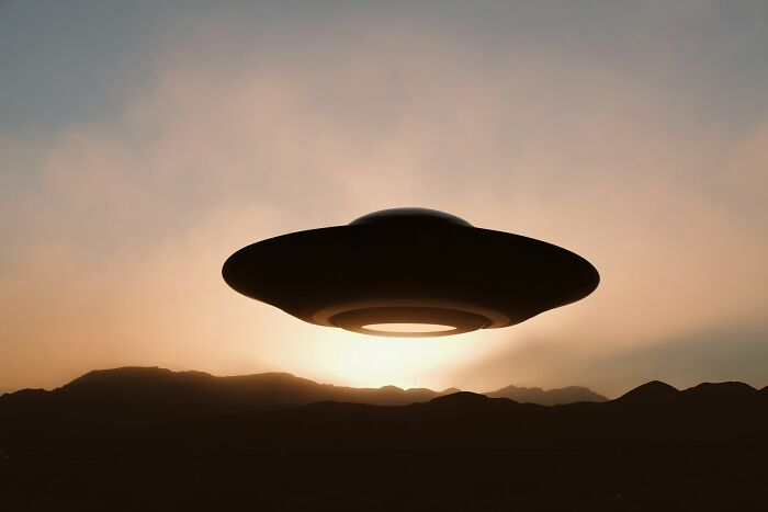 A mysterious UFO hovering over dark mountains at sunset, symbolizing unsolved mysteries and unexplained phenomena.