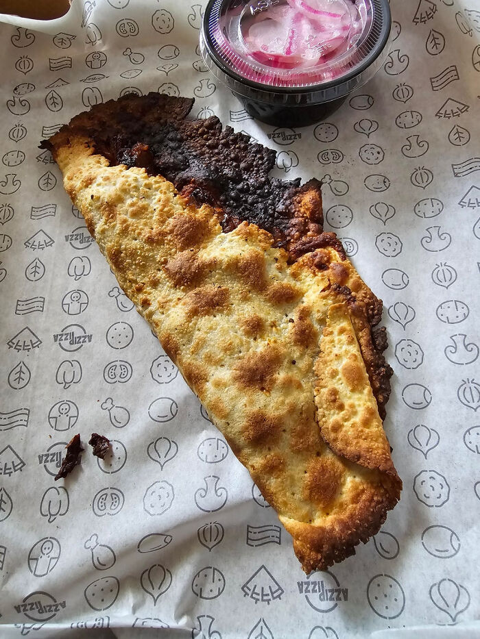 Burnt and misshaped calzone meal that looks nothing like the menu photos served with pickled onions.