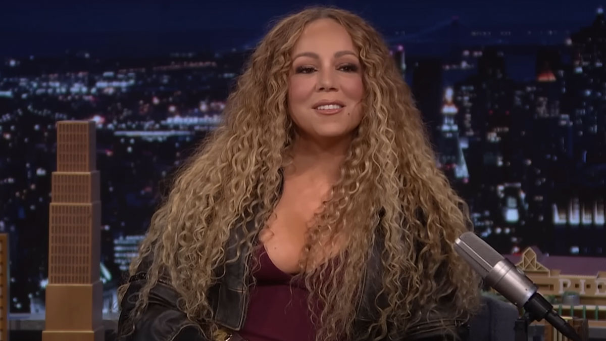 Female celebrity with long curly hair speaking on a late-night show, sharing fascinating secrets about celebrities.