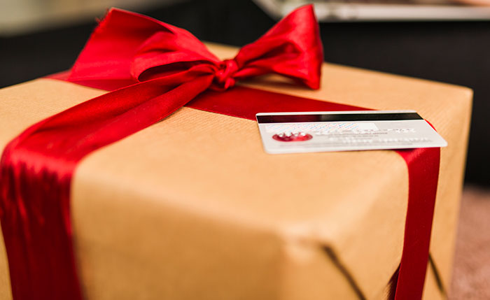 Wrapped gift box with a red ribbon and a credit card, illustrating a white elephant gift refund scenario. Wrapped gift box with a red ribbon and a credit card, illustrating a white elephant gift refund scenario.