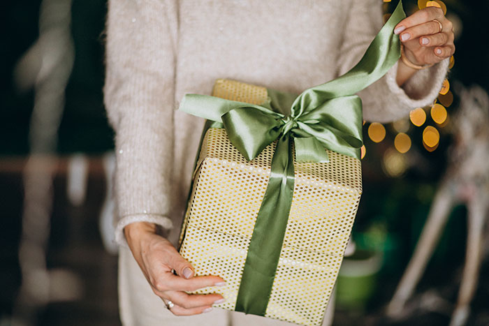 Person holding a wrapped white elephant gift with green ribbon, illustrating a story about stealing and refunding a gift. Person holding a wrapped white elephant gift with green ribbon, illustrating a story about stealing and refunding a gift.
