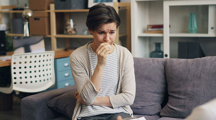 Worried mom sitting on couch at home, upset about teacher's inappropriate note to her son, discussing with someone unseen. Worried mom sitting on couch at home, upset about teacher's inappropriate note to her son, discussing with someone unseen.