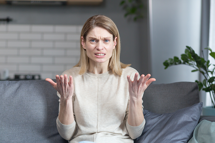 Woman looking frustrated and upset on a couch, illustrating family tension and transphobic conflict after son comes out.