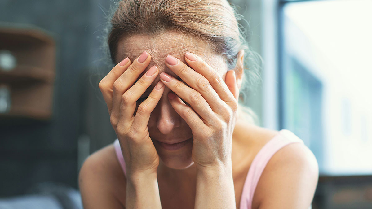 Stressed childfree woman covering her face with hands, reflecting refusal to take responsibility for sister's new baby.