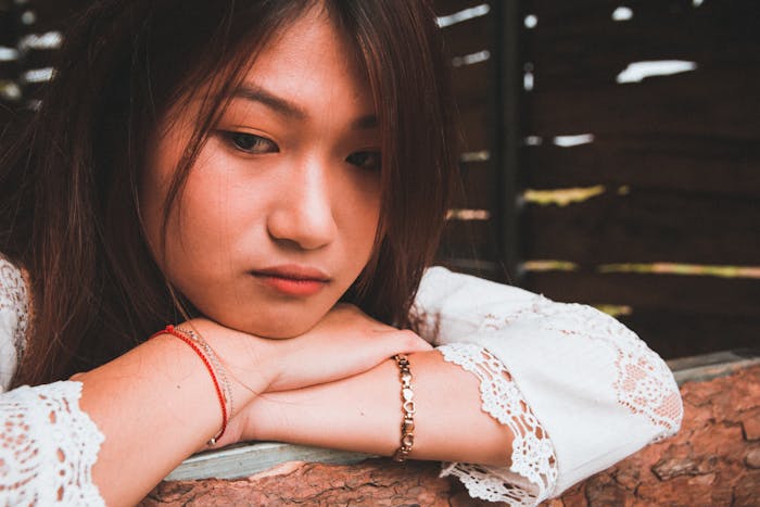 Young woman looks upset and reflective indoors, illustrating a tense family conflict involving hair and relationships.