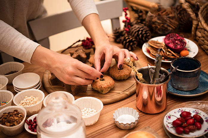 Hands of a woman preparing Christmas treats surrounded by festive decorations highlighting moms doing all the labor during holidays Hands of a woman preparing Christmas treats surrounded by festive decorations highlighting moms doing all the labor during holidays