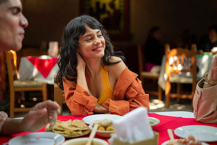 Woman smiling at a family gathering, with future in-laws discussing a prenup after learning about her wealthy background. Woman smiling at a family gathering, with future in-laws discussing a prenup after learning about her wealthy background.