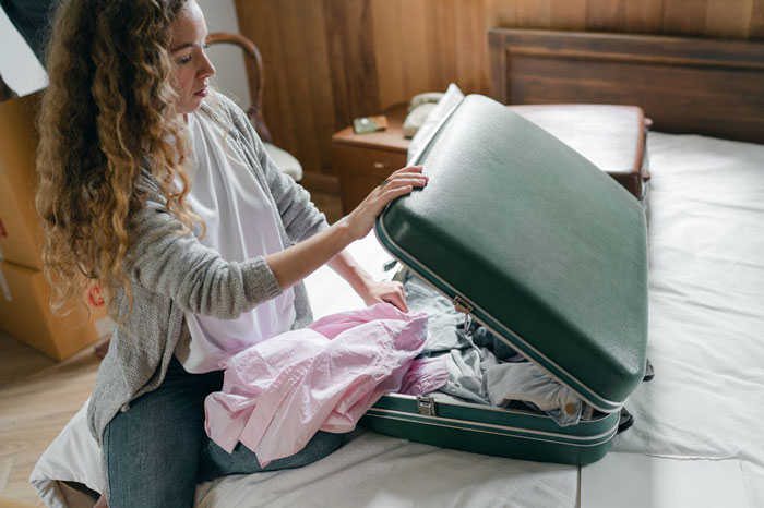 Woman packing suitcase on bed, upset over stepdaughter’s behavior and in-laws’ comments before leaving husband. Woman packing suitcase on bed, upset over stepdaughter’s behavior and in-laws’ comments before leaving husband.