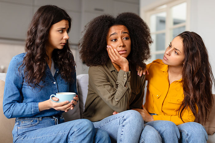 Three women on a couch, mentally unstable woman accused of trying to put gas in bestie's drink, friends looking concerned