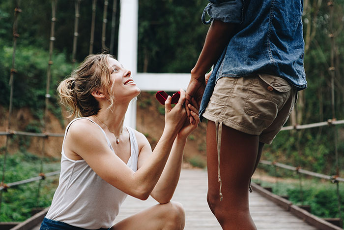 Woman proposing to her boyfriend of 14 years outdoors, holding a ring box, capturing a heartfelt marriage proposal moment. Woman proposing to her boyfriend of 14 years outdoors, holding a ring box, capturing a heartfelt marriage proposal moment.