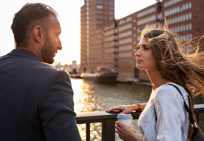 Woman getting a reality check after regretting a divorce, talking seriously with a man near waterfront buildings at sunset. Woman getting a reality check after regretting a divorce, talking seriously with a man near waterfront buildings at sunset.