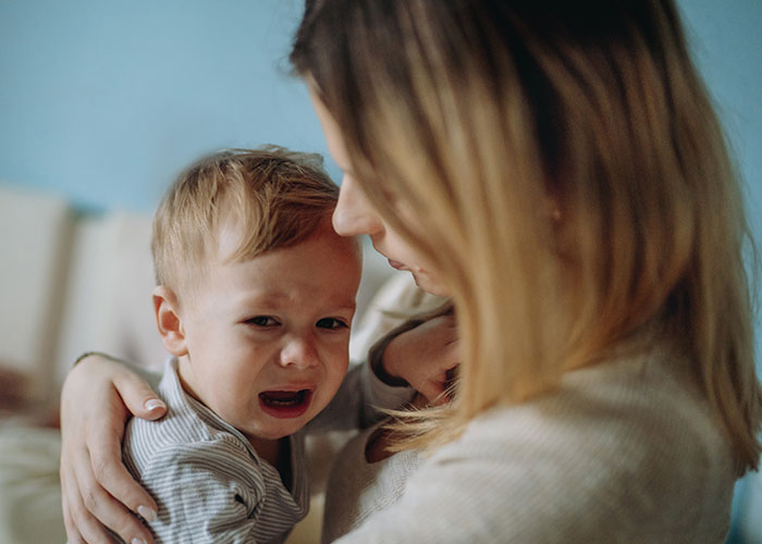 Mother comforting her upset young child indoors, capturing a moment related to trauma and parenting challenges on Christmas.