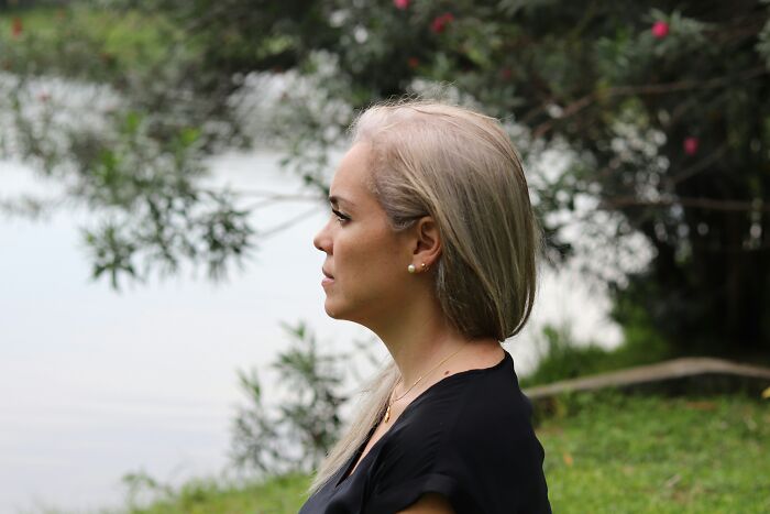 Woman outdoors looking thoughtful near lake, reflecting on spoiling boyfriend and petrol money gift reaction. Woman outdoors looking thoughtful near lake, reflecting on spoiling boyfriend and petrol money gift reaction.