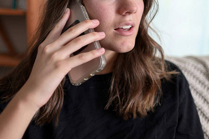 Young woman in black shirt talking on phone, reacting to toxic man venting about traditional wives and logic flaws. Young woman in black shirt talking on phone, reacting to toxic man venting about traditional wives and logic flaws.