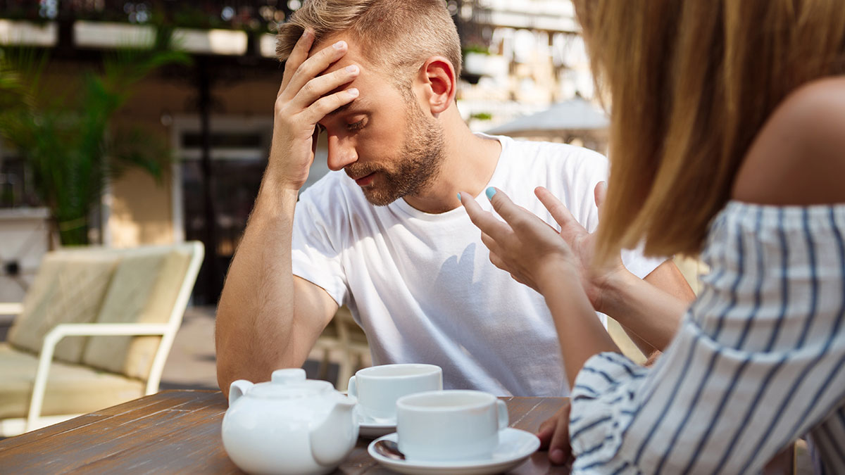 Toxic man frustrated and venting about traditional wives during a tense conversation at an outdoor cafe.