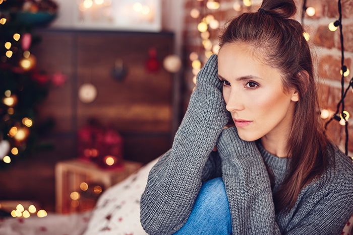 Woman looking horrified indoors near festive Christmas decor after receiving HOA fines for decorations deemed too festive