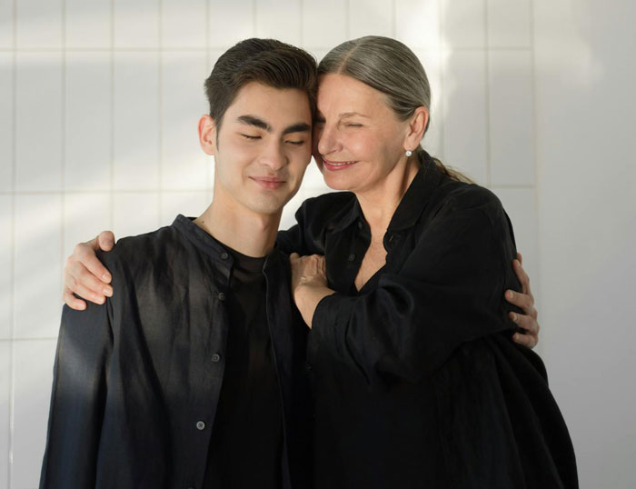 Woman smiling warmly while hugging her son, symbolizing being blinded by flowers, unaware of daughter’s efforts. Woman smiling warmly while hugging her son, symbolizing being blinded by flowers, unaware of daughter’s efforts.