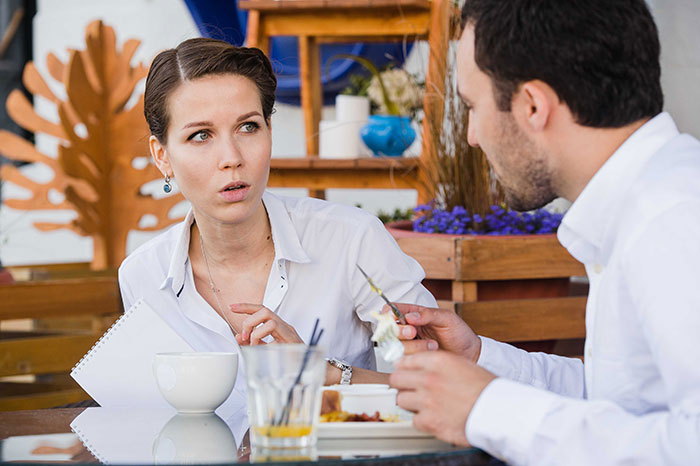 Woman at a table not giving in to social pressure from coworkers, showing confidence despite awkward feelings.