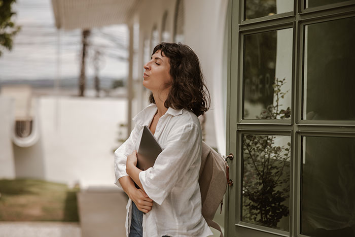 Woman standing outside with a laptop, showing confidence and not giving in to social pressure from coworkers.