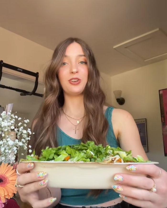 Woman holding a large Chipotle bowl testing if orders under male names get more food with fresh ingredients visible Woman holding a large Chipotle bowl testing if orders under male names get more food with fresh ingredients visible