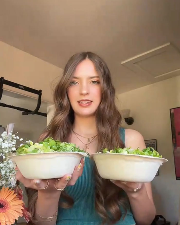 Young woman holding two Chipotle bowls comparing food portions to test order differences under male names Young woman holding two Chipotle bowls comparing food portions to test order differences under male names