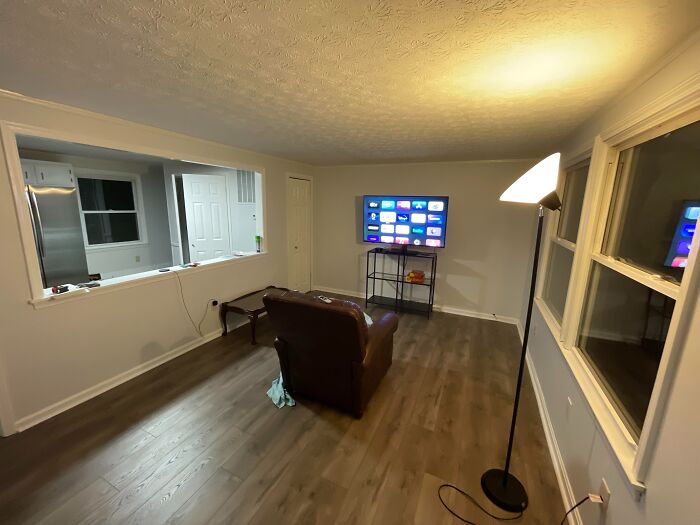Minimalist living room with wooden floors, a single armchair, and a TV, illustrating home service professionals' client visits.