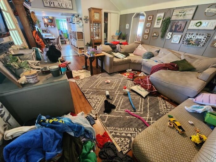 Messy family living room cluttered with clothes, toys, and household items seen by home service professionals.