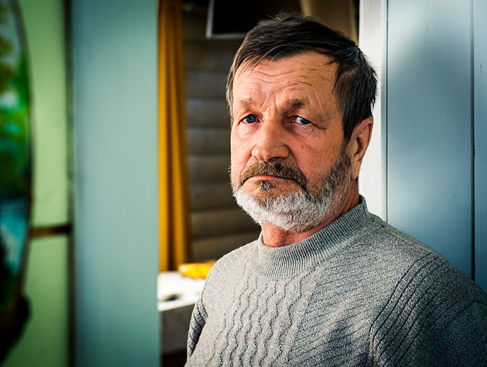 Older man with a serious expression leaning against a wall, reflecting on brand mistakes that led to boycotts by customers.