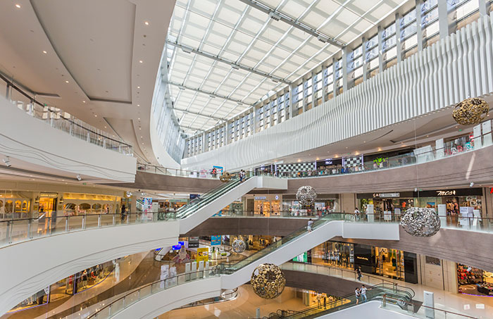 Spacious modern shopping mall interior with escalators and multiple brand stores showcasing retail mistakes and boycotts.