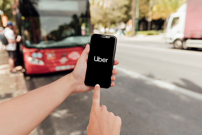 Person holding smartphone with Uber app open, illustrating brand mistake that annoyed people leading to boycott.
